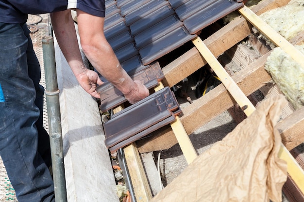 A roofer laying tile on the roof