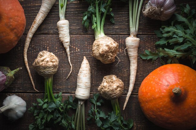 Photo roots of parsley celery with leaves and pumpkin on brown boards horizontal