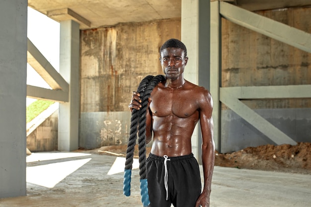 Rope workout Sport man doing battle ropes exercise outdoor Black male athlete exercising doing functional fitness training with heavy rope