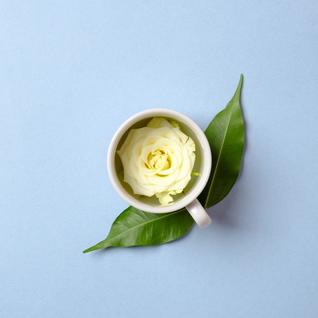 Rose flower petal in tea cup with green leaves