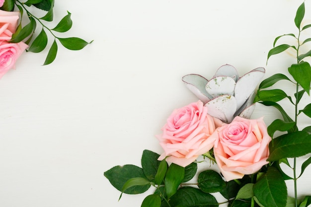 Rose fresh flowers with leaves on table from above with copy space flat lay frame