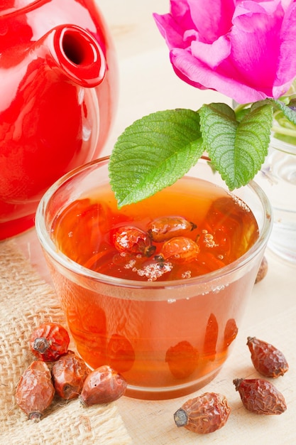 Rose hips tea red teapot and rosehip flowers