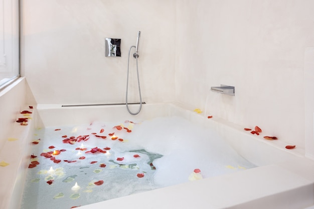 Rose petals put in bathtub for romantic bathroom atmosphere bubble bath arranged for honeymoon couple