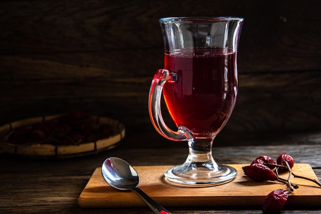 Rosehip tea in a glass cup on a wooden background.