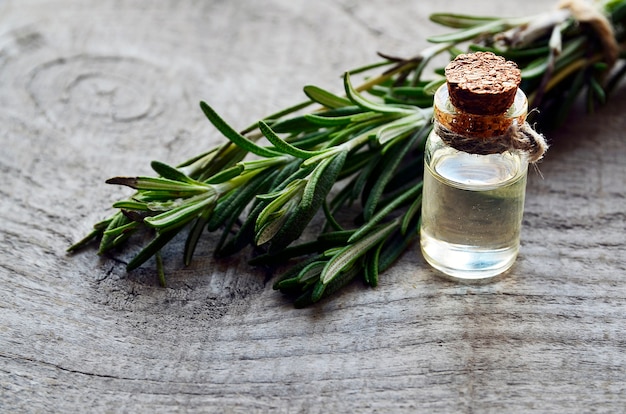 Rosemary essential oil in a glass bottle and rosemary leaves