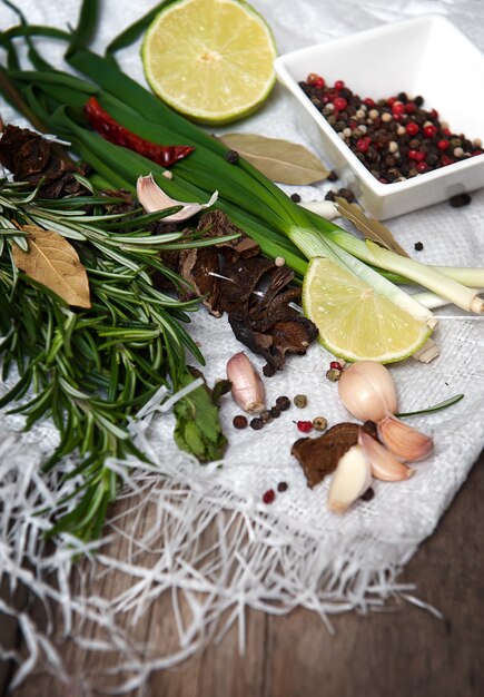 Photo rosemary, lime, chili pepper, garlic, dry mushrooms on wooden table.