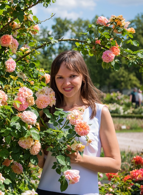 Roses garden and smiling happy woman on sunny summer day.