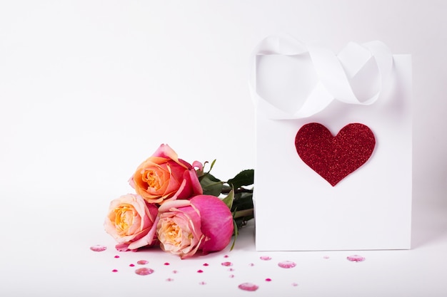 Roses and present gift in paper pack with red heart