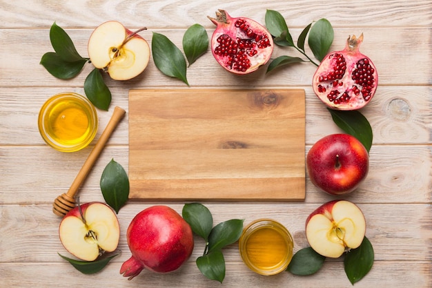 Rosh hashanah jewish holiday concept honey apple and pomegranate with cutting board close up