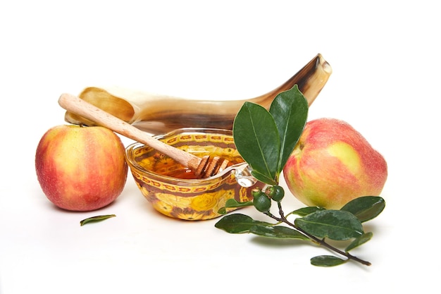 Rosh hashanah jewish new year holiday concept An appleshaped bowl with honey apples a shofar are traditional symbols of the holiday Isolated on white background