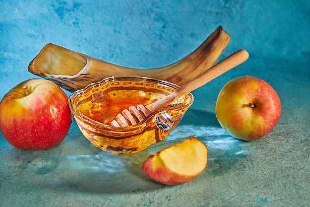 Rosh hashanah jewish new year holiday concept Appleshaped bowl with honey apples shofar are traditional symbols of the holiday