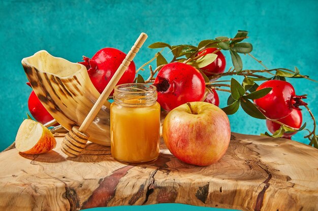 Rosh hashanah jewish new year holiday concept Bowl in the shape of an apple with honey apples pomegranates shofar on a blue background