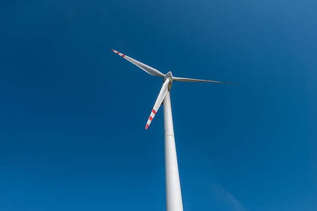 Rotating blades of a windmill propeller on blue sky background Wind power generation Pure green energy