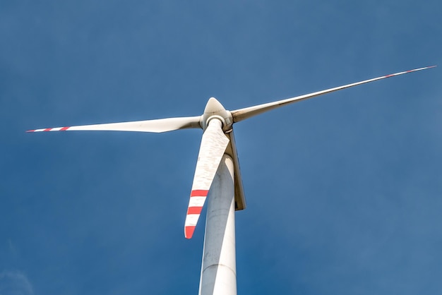 Rotating blades of a windmill propeller on blue sky background Wind power generation Pure green energy