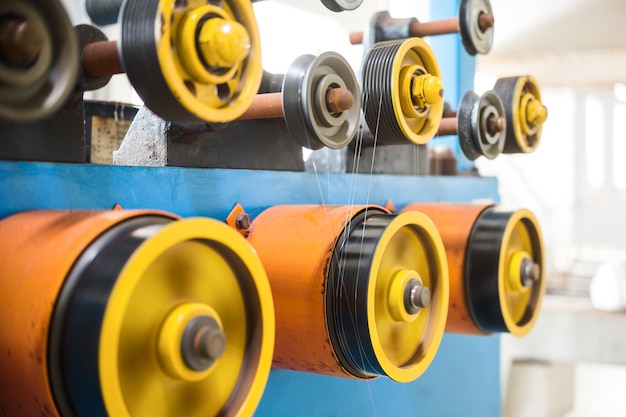 A rotating wheel rewinds a thin silver wire