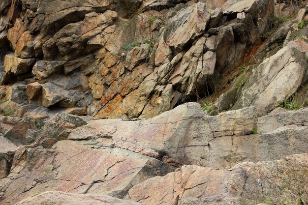 Rough brown stone wall Texture of old stone rock weathered surface Closeup