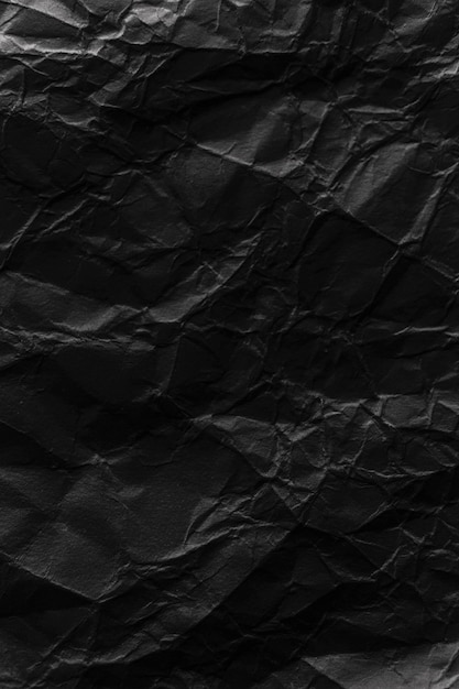 Rough damaged crumpled black paper texture background with wrinkles