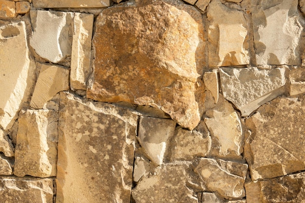 Rough surface of stone wall on a sunny day. Dry white block texture in sunlight