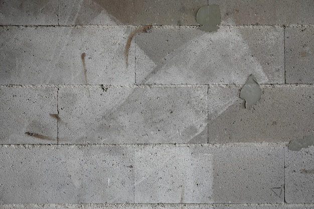 Rough surface texture wall of concrete blocks with paint traces and plaster at a construction site