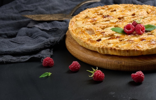 Round baked apple pie on a black table