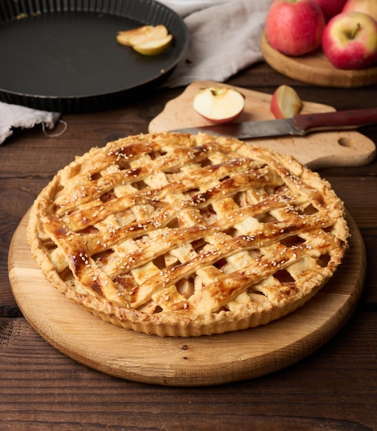 Round baked apple pie on a brown wooden table top view