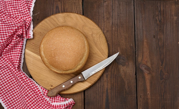 Round baked bread on a wooden board brown table