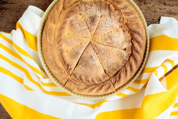 Round cake with a yellow napkin on a wooden background top view