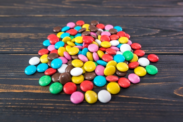 Photo round colored candies on a wooden surface.