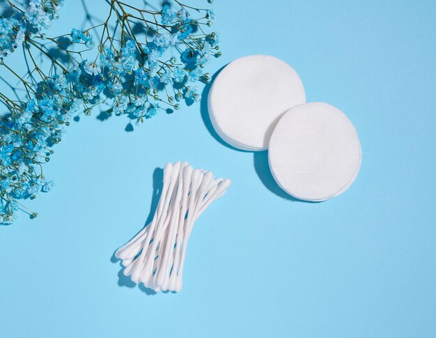 Photo round cotton cosmetic pads and cotton buds on a blue background top view