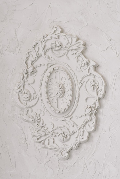 Round decorative clay stucco relief molding with floral ornaments on white ceiling in abstract classical style interior