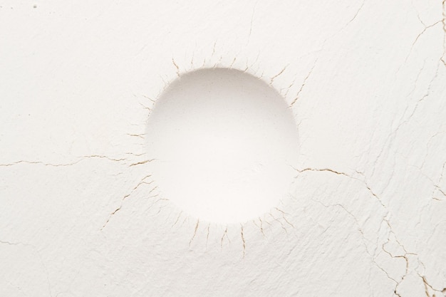 Round deep print with cracks emanating from it on a white powder. Textured background. Copy space