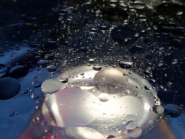 Round drops of different sizes Drops of oil in water with color reflection Blue white and black elements Circles and spheres Microabstraction Side lighting Glare in the water