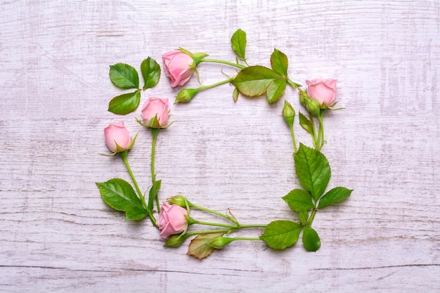 Round frame of delicate flowers Pink roses on a wooden background