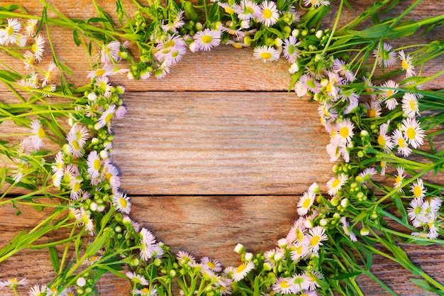 Round frame made of chamomile on wooden vintage background 