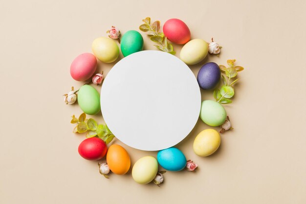 Round frame multicolored Easter eggs with white blank paper on a brown background closeup space for text blank for design selective focus tinted image