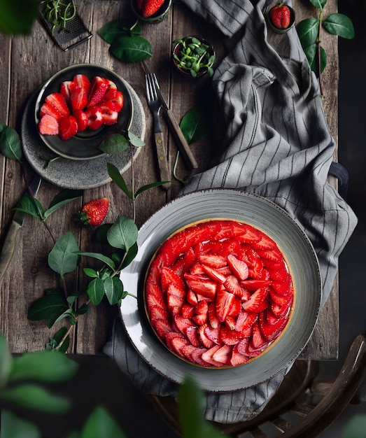 Round fruit tart cake with strawberries and white cheese cream on the wooden table and wooden old chair near