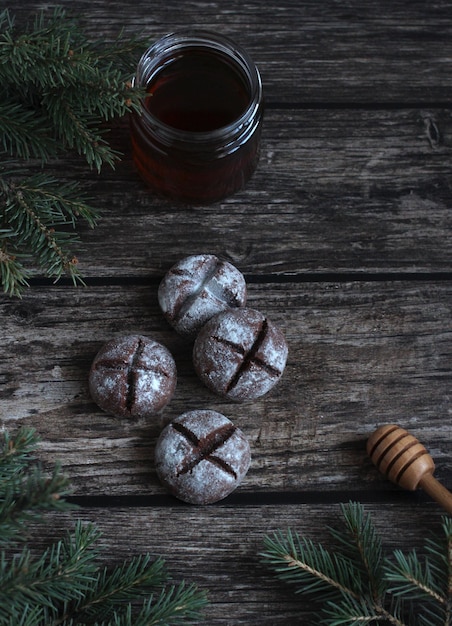 Round homemade gingerbread with honey and powdered sugar on a wooden background with spruce branches