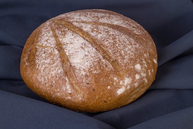 Round loaf of buckwheat bread on dark background. Top view