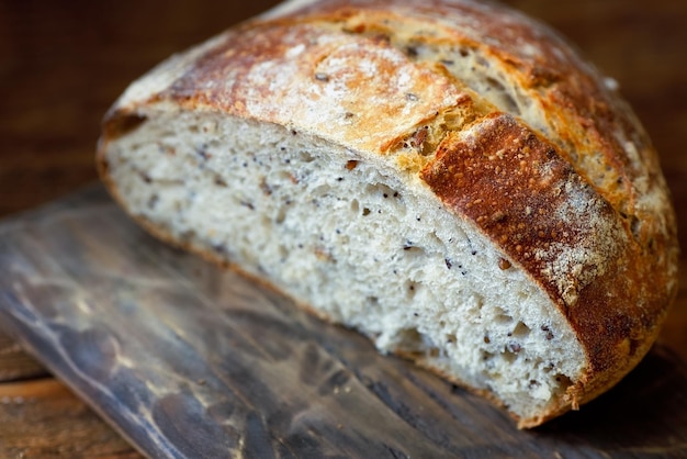 A round loaf of wholegrain homemade bread without yeast lies on a wooden board Fresh pastries for a healthy diet