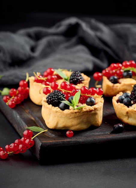 Round mini fruit pie on a wooden board close up