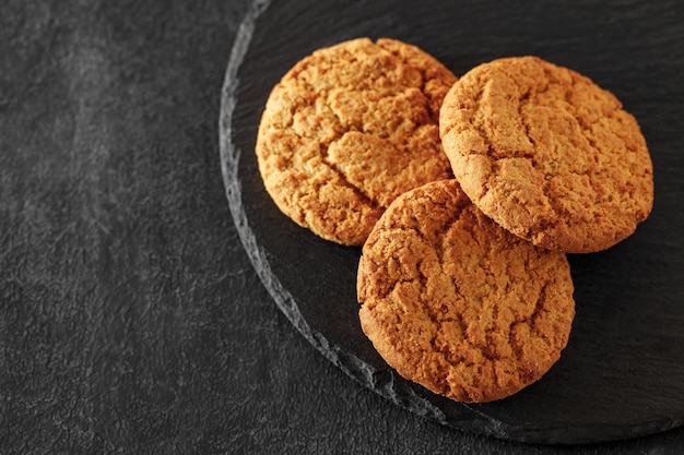 Round oatmeal cookies three pieces on slate stone plate round dark background selective focus