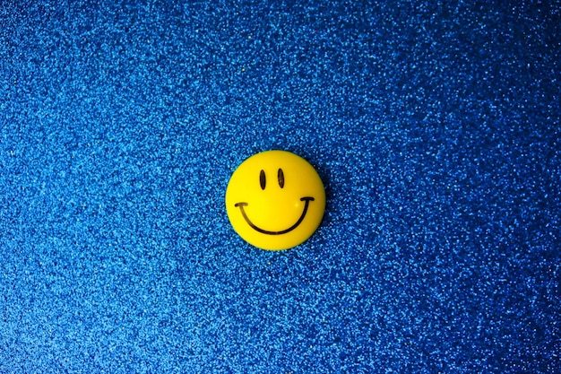 Round plastic yellow joyful smiling smiling toy round face Emoji on a blue background