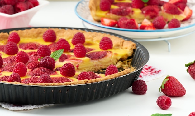 Round quiche with red strawberries and raspberries on a white table top view