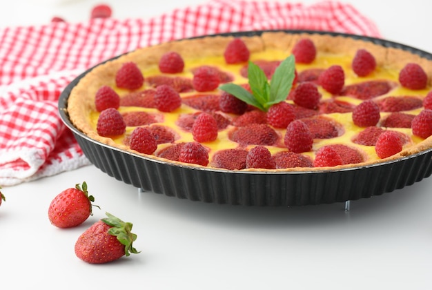 Round quiche with red strawberries and raspberries on a white table top view