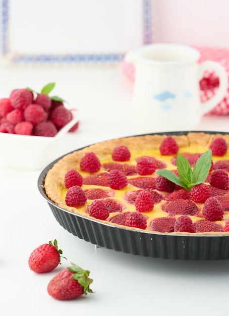 Round quiche with red strawberries and raspberries on a white table