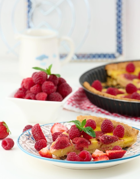 Round quiche with red strawberries and raspberries on a white table