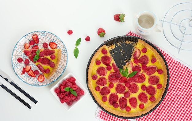 Round quiche with red strawberries and raspberries on a white table