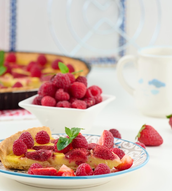 Round quiche with red strawberries and raspberries on a white table