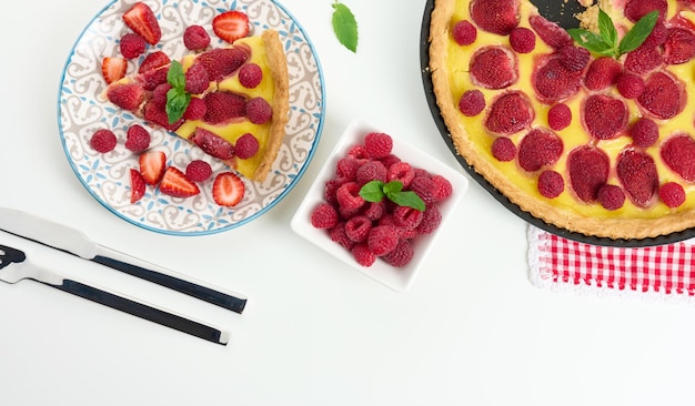 Round quiche with red strawberries and raspberries on a white table