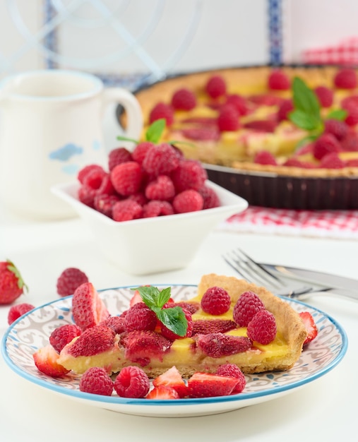 Round quiche with red strawberries and raspberries on a white table